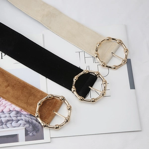 Detail of three velvet waist belts with gold bamboo-textured circular buckles on magazine