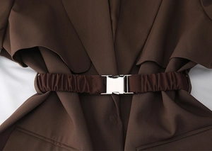 Détail d'une large ceinture élastique marron foncé avec une boucle en métal argenté