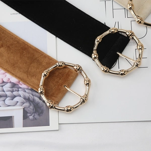 Close-up of suede waist belts with round bamboo-style metal buckles in black and caramel