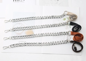 Close-up of beige, black and brown canvas bag straps with chunky silver metal chains