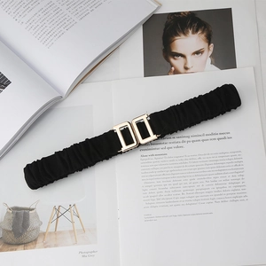 Detail of black elastic waist belt with gold interlocking D-shaped buckle on magazine