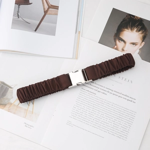 Large ceinture élastique marron foncé avec boucle argentée sur fond de magazine de mode
