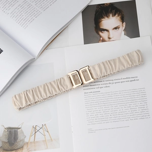 Close-up of beige elastic waist belt with gold double D buckle on fashion magazines