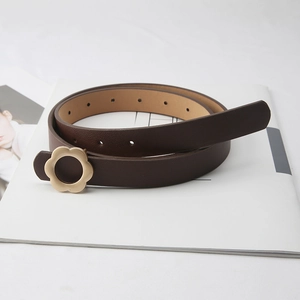 Ceinture fine en cuir marron foncé avec boucle fleur dorée sur un fond minimaliste chic