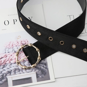 Detail of black velvet belt with golden bamboo-style buckle and metal eyelets