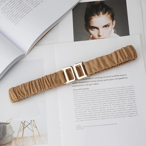 Vintage brown elastic waist belt with gold buckle on a stylish fashion book background