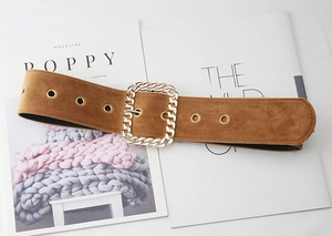 Détail de la ceinture marron en daim avec boucle à chaîne dorée et œillets en métal