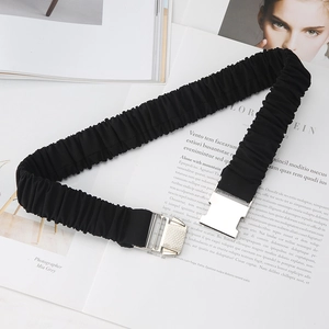 Détail d'une ceinture élastique noire avec boucle argentée posée sur un magazine