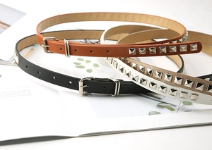 Detailed close-up of three rivet belts in black, brown and white on a magazine