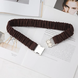 Détail d'une ceinture élastique plissée marron café avec boucle argentée sur magazine
