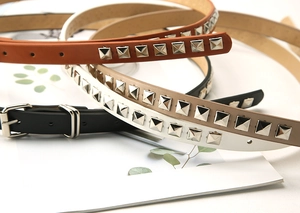Detail view of slim studded belts in black, brown, and beige with metallic rivets