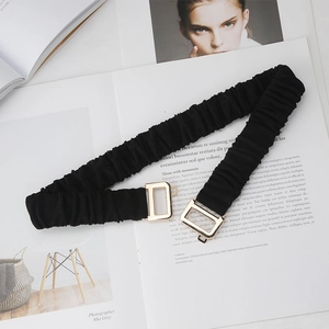 Detail of black pleated elastic waist belt with gold rectangular metal interlocking buckle
