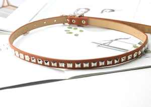 Close-up of brown leather thin belt featuring silver square studs and fine stitching