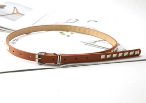Detailed macro view of a brown slim leather belt with silver square rivet accents