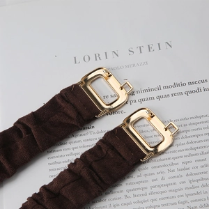 Detailed macro view of dark brown elastic ruched straps with gold rectangular metal hooks