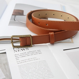 Vintage brown leather belt for women with bronze metal buckle on fashion magazine