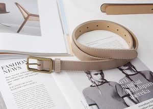 Macro shot of khaki thin faux leather belt with vintage bronze rectangular buckle