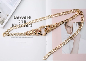 Détail d'une grosse ceinture chaîne dorée à maillons avec boucles anneaux croisées
