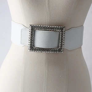 Detail of wide white elastic belt with a large silver buckle encrusted with clear rhinestones
