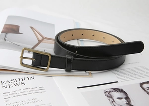Close-up of black leather belt with vintage bronze metal buckle on fashion magazine