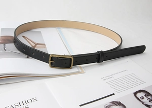 Detail of a vintage black leather belt featuring a textured bronze metal square buckle