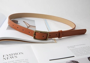 Macro detail of brown leather belt with vintage bronze rectangular buckle on fashion magazine