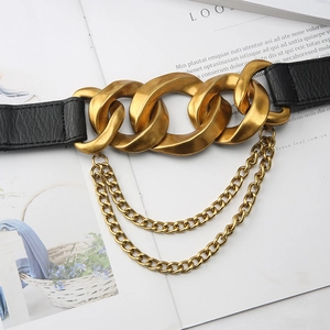 Detail of a wide black elastic belt featuring a matte gold chunky chain and hanging links