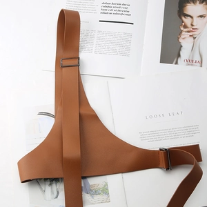 Dettaglio cintura harness in pelle marrone con fibbie in metallo su rivista di moda