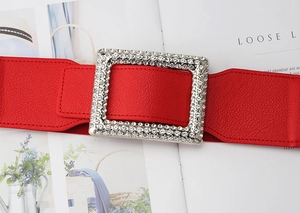 Macro shot of red leather wide belt with a sparkling rhinestone rectangle buckle detail