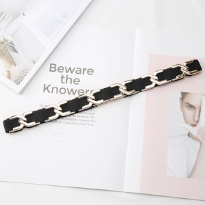 Ceinture élastique noire pour femme avec chaîne dorée posée sur un magazine de mode