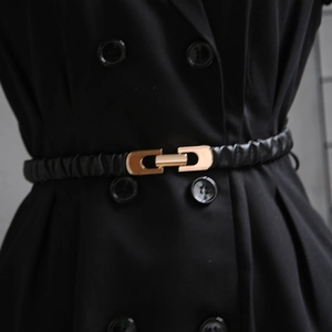 Detail of a thin black elastic waist belt with a gold metal oval buckle on a dress