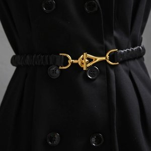 Close-up of black elastic waist belt featuring a polished gold geometric T-bar metal buckle