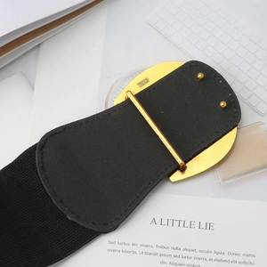 Détail d'une large ceinture élastique noire avec une boucle en métal doré gravée Y319