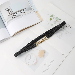 Women's black ruched elastic waist belt with vintage gold metal buckle on magazine