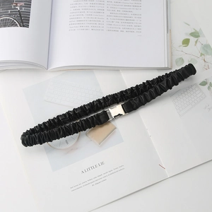 Close-up of black elastic waist belt with textured pleats and silver square metal buckle