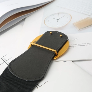 Détail d'une large ceinture élastique avec boucle en métal doré et numéro gravé