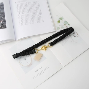 Detailed shot of elastic black waist belt with polished gold-tone ring buckle closure