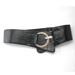 Detail of wide black belt with crocodile pattern leather and large round gold buckle