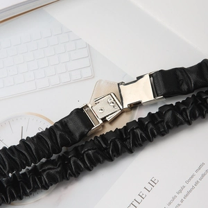 Detail of black elastic pleated belt with a polished silver buckle on white background