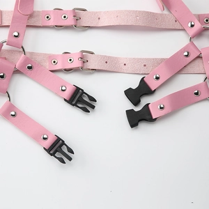 Dettaglio dell'imbracatura rosa in pelle PU con anelli in metallo e fibbie argentate