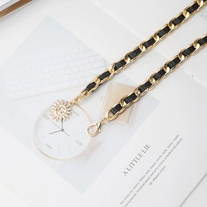 Detail of vintage gold chain belt with black leather weave and round sun charms