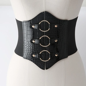 Detail of black crocodile texture corset belt with gold metal rings on a model