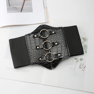 Detailed close-up of a wide black corset belt with gold metal rings and crocodile texture