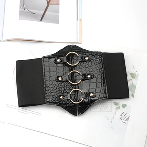 Detail of black wide elastic waist belt with crocodile texture and gold metal rings