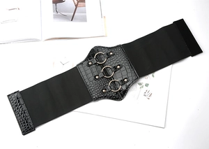 Detail of black elastic waist belt with gold rings and crocodile pattern texture