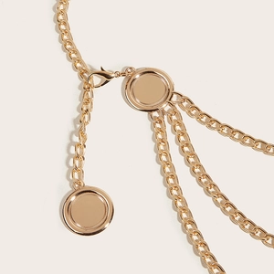 Macro shot of multi-layer gold metal waist chain with round pendants and curb links