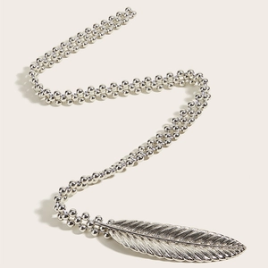 Close-up of flexible silver bead chain waist belt featuring a detailed metal feather pendant