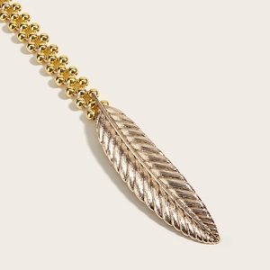 Close-up of golden feather buckle detail and multi-strand metal bead chain decoration