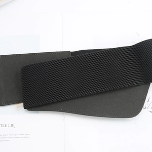 Detail of a black elastic waist belt with faux leather texture and fine stitching