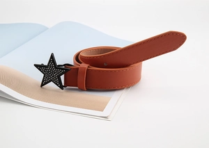 Détail d'une ceinture en cuir brun-rouge avec boucle étoile noire et strass brillants